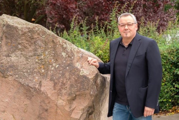 Local mayor Oliver Krupp leans against a large stone