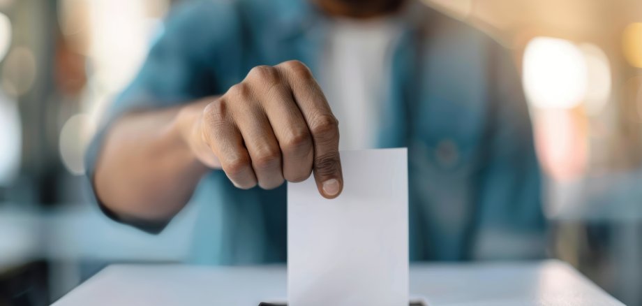 A person throws a piece of paper into an urn.